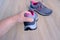 Female hands inspecting a pair of gray new womens trekking shoes with pink trim, tied with laces, concept of comfortable sports