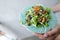 Female hands keeping thai salad with shrimps on white plate.