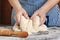 Female hands knead the dough on a floury table.