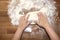 Female hands knead the dough on a wooden table, sprinkled with flour, close-up, selective focus, home cooking concept, copy space