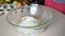 Female hands kneading dough in flour on the table, adds egg to flour, adds ingredients baking powder, sugar