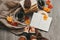 Female hands knitting sweater on the floor with autumn leaves and cup of coffee