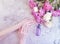 Female hands manicure cream cosmetic flower peony on gray concrete background