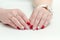 Female hands with manicure, red nail polish, drawing with cherries. Wrist watch. White background.