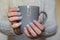 Female hands with manicured fingernails holding grey cup. Health, beauty, hands care