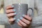 Female hands with manicured fingernails holding grey cup. Health, beauty, hands care