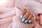 Female hands matte blue gradient manicure close up view on pink knitted sweater background