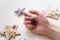 Female hands with Merry Christmas reindeer manicure on finger nails holding decorative pine cone.