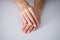 Female hands with a nice manicure on gray background, nude