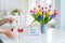 Female hands are opening gift box on marble table with colorful spring flowers bouquet in vase and lightbox with words Best mom