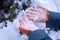 Female hands in orange gloves with stuck snow.