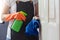 Female hands in orange rubber gloves cleaning on touching surface of door, doorknob with blue microfiber cleaning cloth and green