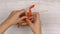 Female hands pack a gift with red ribbon on a light wooden table.