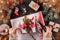 Female hands packs a Christmas gift box with red ribbon on holiday background with Fir branches, pine cones.