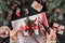 Female hands packs a Christmas gift box with red ribbon on holiday background with Fir branches, pine cones.