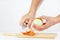 Female hands peeling raw onion with a knife on a cutting board