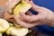 Female hands peeling skin off of a yellow apple with a knife