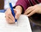 Female hands with a pencil write on a paper