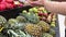 Female hands and pineapple close-up. Pineapple, mango and pomegranate on blurred supermarket background.