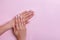 Female hands on pink background, top view