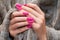 Female hands with pink nail design. Mate pink nail polish manicure. Female model hands with beige fluffy fabric