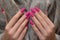 Female hands with pink nail design. Mate pink nail polish manicure. Female model hands hold gray fluffy fabric