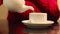 Female hands pour hot tea into white cup on table in cafe, shallow dof