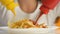 Female hands pouring ketchup and mustard into french fries, extra calorie meal