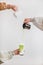 Female hands pouring matcha tea and milk into glass