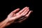 Female hands praying with palms up arms outstretched. Black background