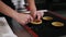 Female hands of professional confectioner forming dough for baking tartlets. Black working surface. Indoors, culinary