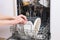 Female hands put dirty dishes in the dishwasher. Close-up of the dishes placed in the dishwasher