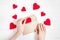 Female hands put red hearts in a congratulatory envelope on a white wooden background  happy valentine`s day background  love