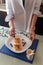 Female hands putting blueberry on traditional syrniki or cottage cheese pankaces and honey pot with blue napkin on kitchen table.