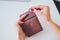 Female hands is putting coins in wallet on pastel faded background