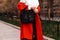 Female hands on a red classic jacket and white blouse and black bag.