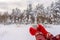 Female hands in red knitted gloves holding tea or coffee mug against winter landscape with snow covered forest in cloudy day. Cozy