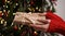 Female hands in red sweater hold Christmas New Year gift box on background of Christmas tree.Giving gifts for holidays.Christmas