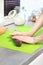 Female hands roll the dough for baking on a green silicone coffee table lying on the kitchen counter.