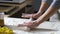 Female hands roll out dough with rolling-pin on wooden table covered in flour