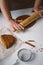 Female hands roll out raw ginger dough with a rolling pin on a white tabl