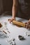 Female hands roll out raw ginger dough with a rolling pin on a white tabl