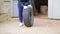 Female hands rolling out a car tire with a disc out of the garage