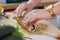 Female hands rolling a sushi in fried sesame seeds. Making a complicated dish like sushi at home