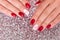 Female hands with romantic manicure, red gel polish, hearts on nails