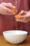 Female hands separate the egg white from the yolk over a bowl in the kitchen