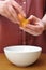 Female hands separate the egg white from the yolk over a bowl in the kitchen