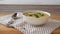 Female hands serve pumpkin and carrot soup in bowl with dill and spicies on a kitchen.