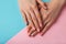 Female hands showcasing pastel stylish trendy manicure against a duotone blue and pink background