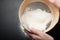 Female hands sift flour on a black background, top view